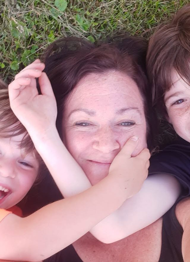 Melanie with her two boys, lying in the grass